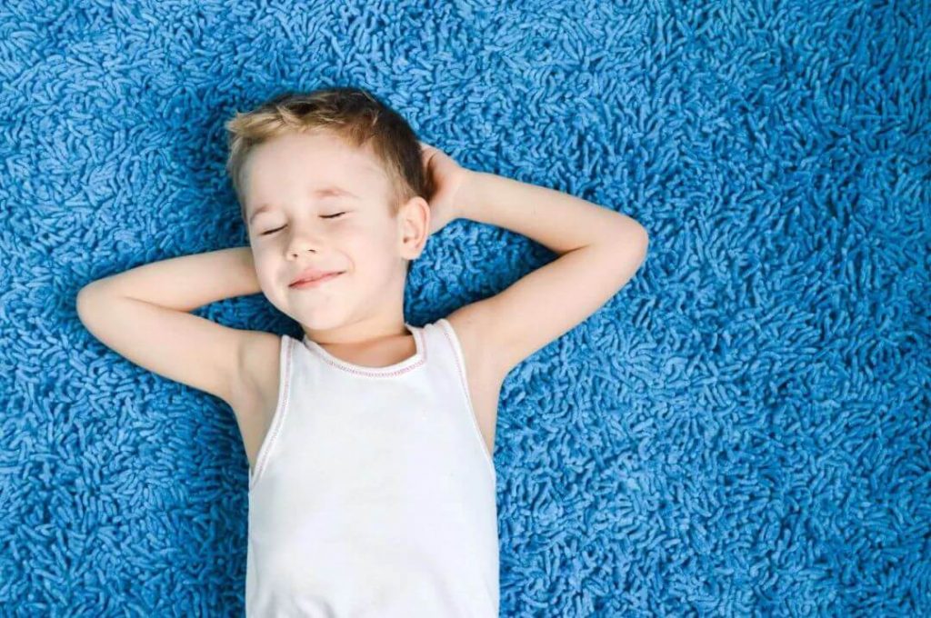 kid laying on a carpeted floor