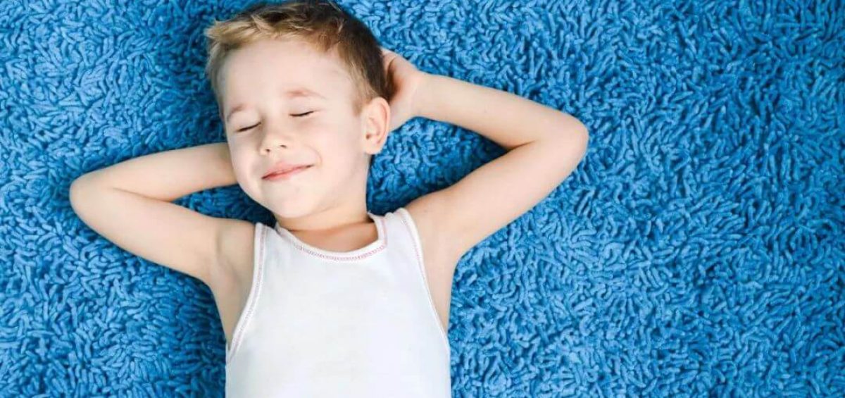 kid laying on a carpeted floor